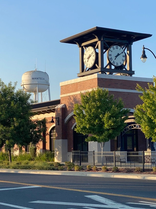 an image of manteca, california showcasing their transit center (bus station) and iconic clock and water tower visible in the background