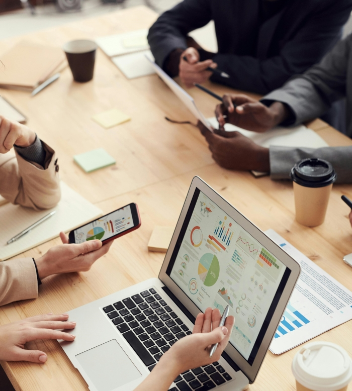 group of professionals analyzing data charts on a laptop and smartphone during a business meeting